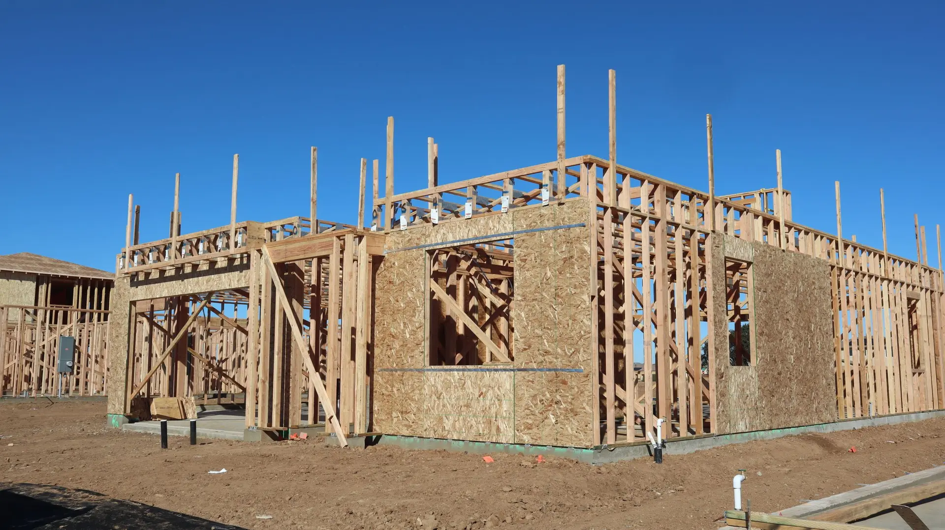 Wood wall framing of a small one-story building on a bare lot