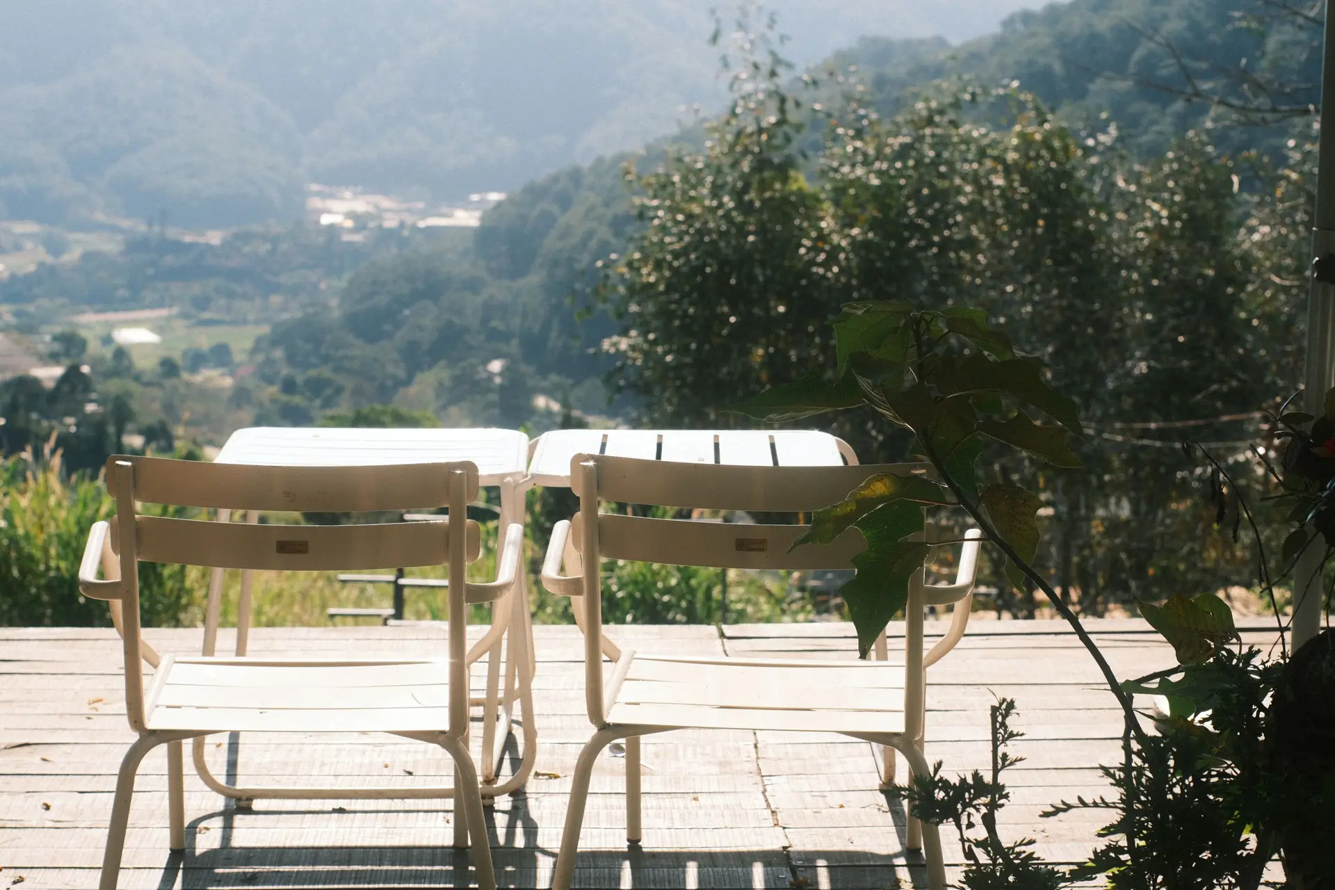 Patio table and chairs on a terrace above a wooded mountain valley