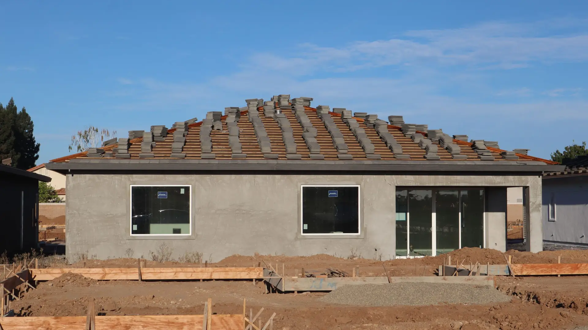 New single-story house with a tile roof on a bare graded lot