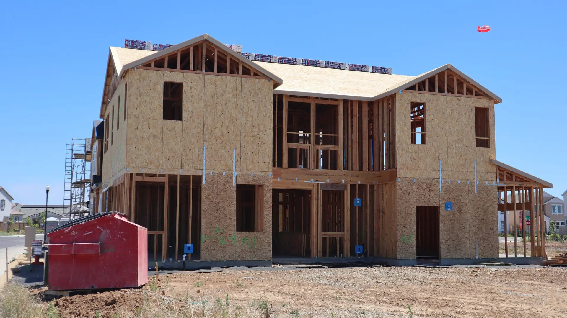 Two-story house framed and sheathed with a dumpster on the lot