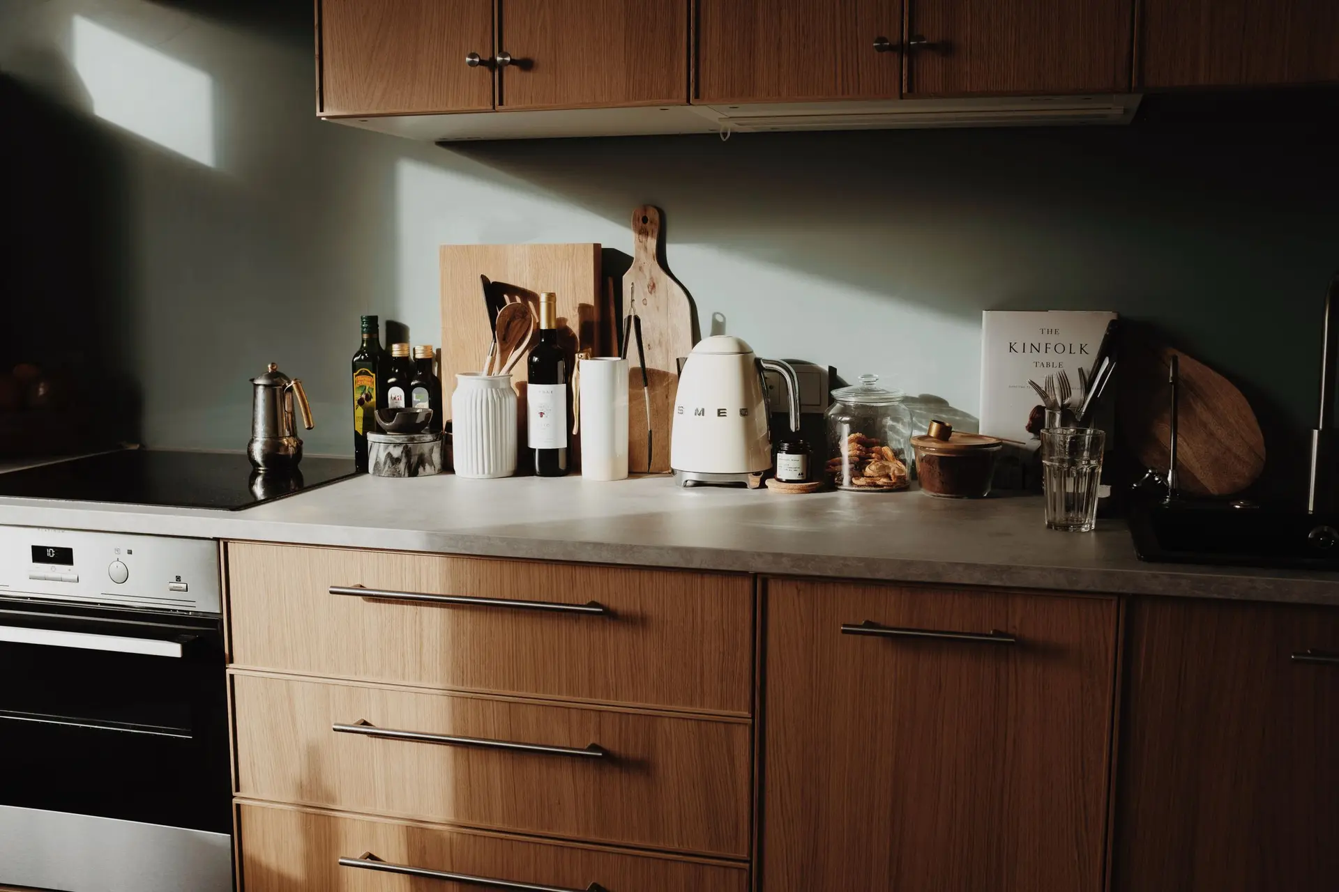 Kitchen with flat wood cabinet fronts and a dark backsplash in morning light