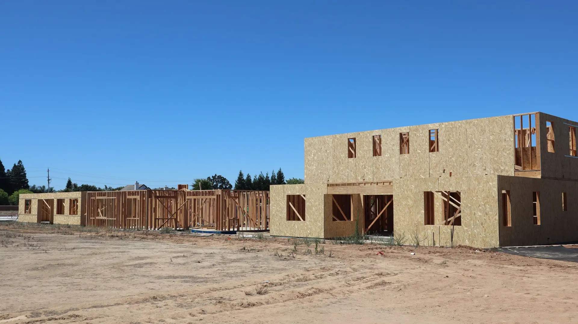 Two-story houses framed and sheathed on a cleared building pad