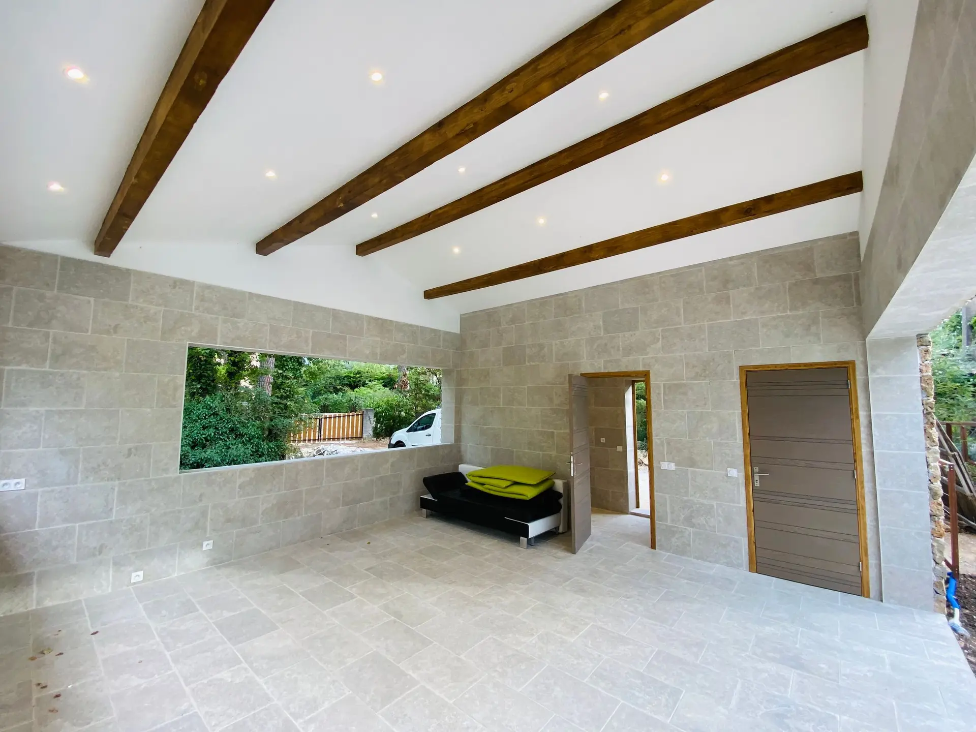 Open room with dark ceiling beams, stone walls and a picture window